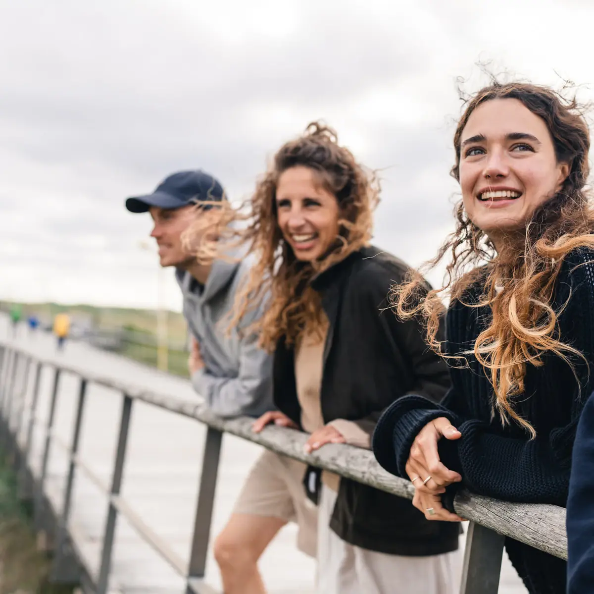 Drei Personen stehen in St. Peter-Ording auf der Seebrücke und lächeln.