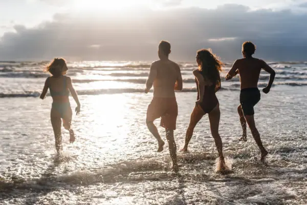 Eine Gruppe von Menschen läuft in die Nordsee am Strandabschnitt von St. Peter-Ording Bad..