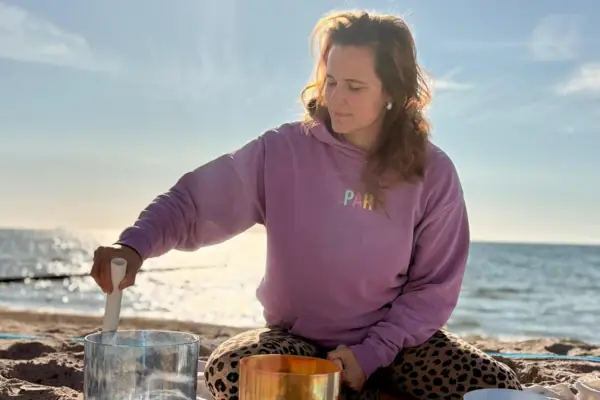 Frau sitzt auf einer Decke am Strand.