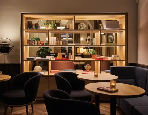 Stilvoller Lounge-Bereich im Urban Nature Hotel Bad Gastein mit Regal, Vasen, Kerzenlicht und gemütlichen Sesseln