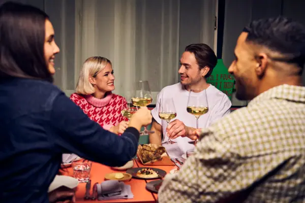 Anstossen Eine Gruppe von Menschen sitzt um einen Tisch mit Weingläsern.