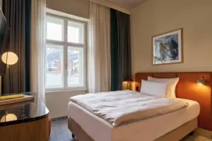 Einzelzimmer Bett mit Tisch und Lampe in einem Zimmer mit Fenster.