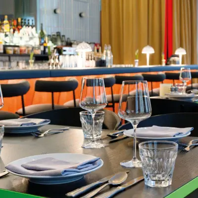 Ein eingedeckter Tisch in einem Restaurant mit Tellern, Gläsern und Servietten.