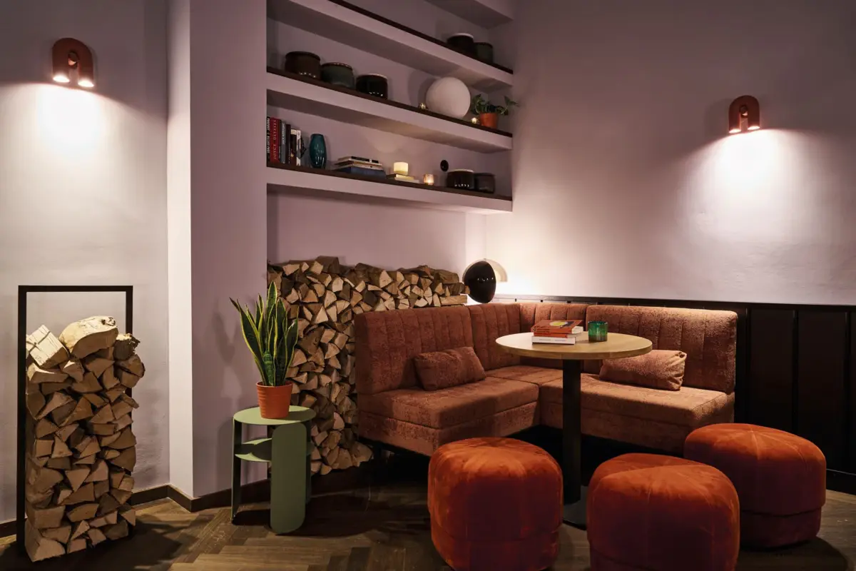 Separee in der Schlossbar im Badeschloss Bad Gastein Gemütliche Lounge-Ecke mit Kaminholz, Bücherregal, Polstermöbeln und stimmungsvoller Beleuchtung in einem modernen Hotel