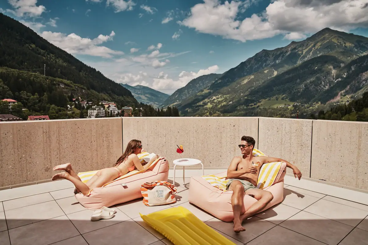 Poolbereich im Urban Nature Bad Gastein Ein Mann und eine Frau auf einer Terrasse mit Bergblick.