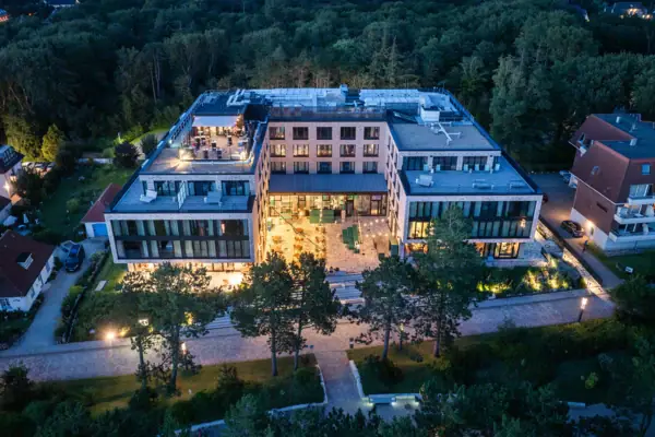 Das Urban Nature Hotel St. Peter-Ording mit umliegenden Bäumen von oben bei Dämmerung fotografiert.
