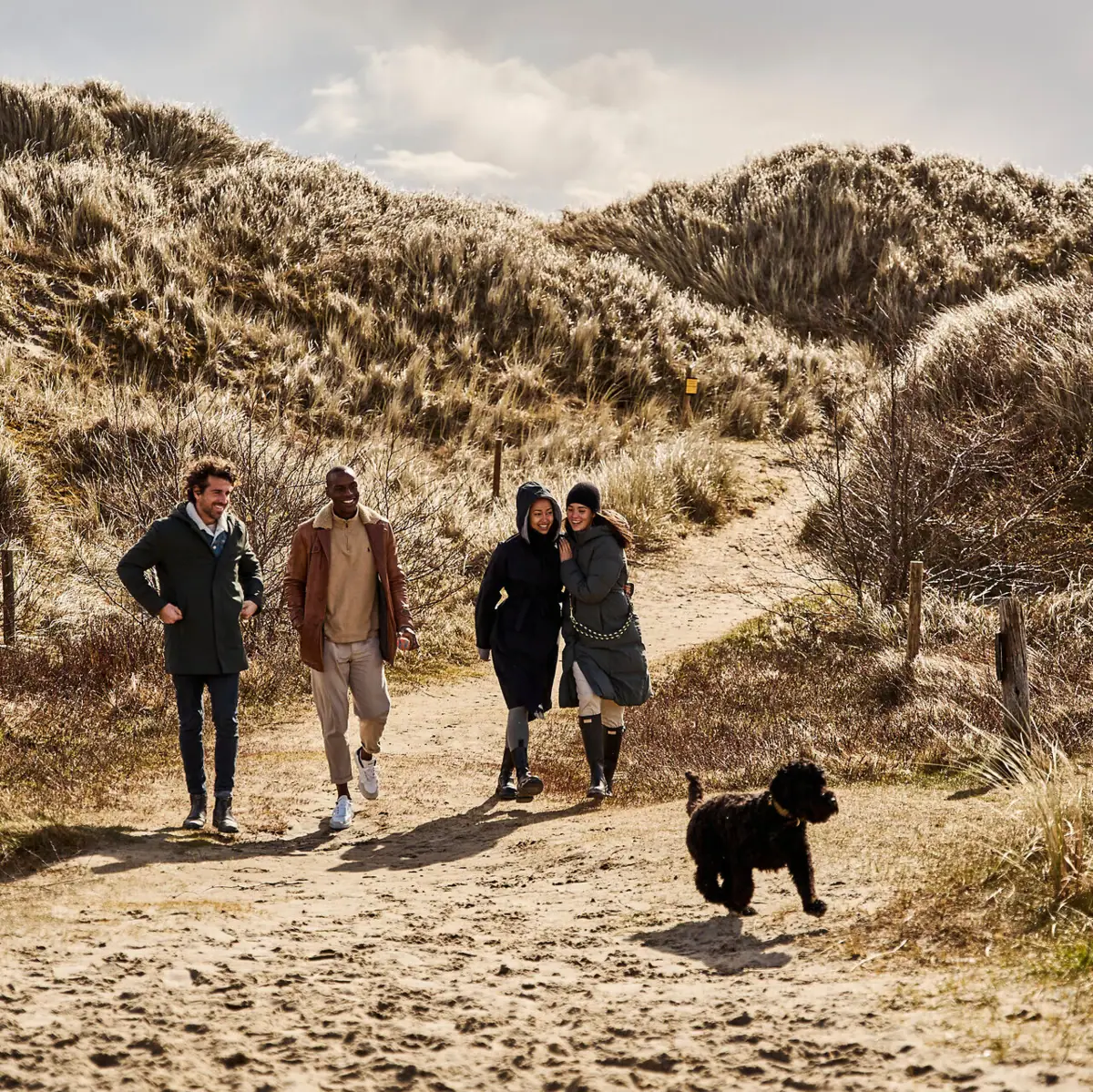 St. Peter-Ording mit Hund Eine Gruppe von Menschen geht auf einem Weg durch Dünen zum Strand mit einem Hund in St. Peter-Ording.