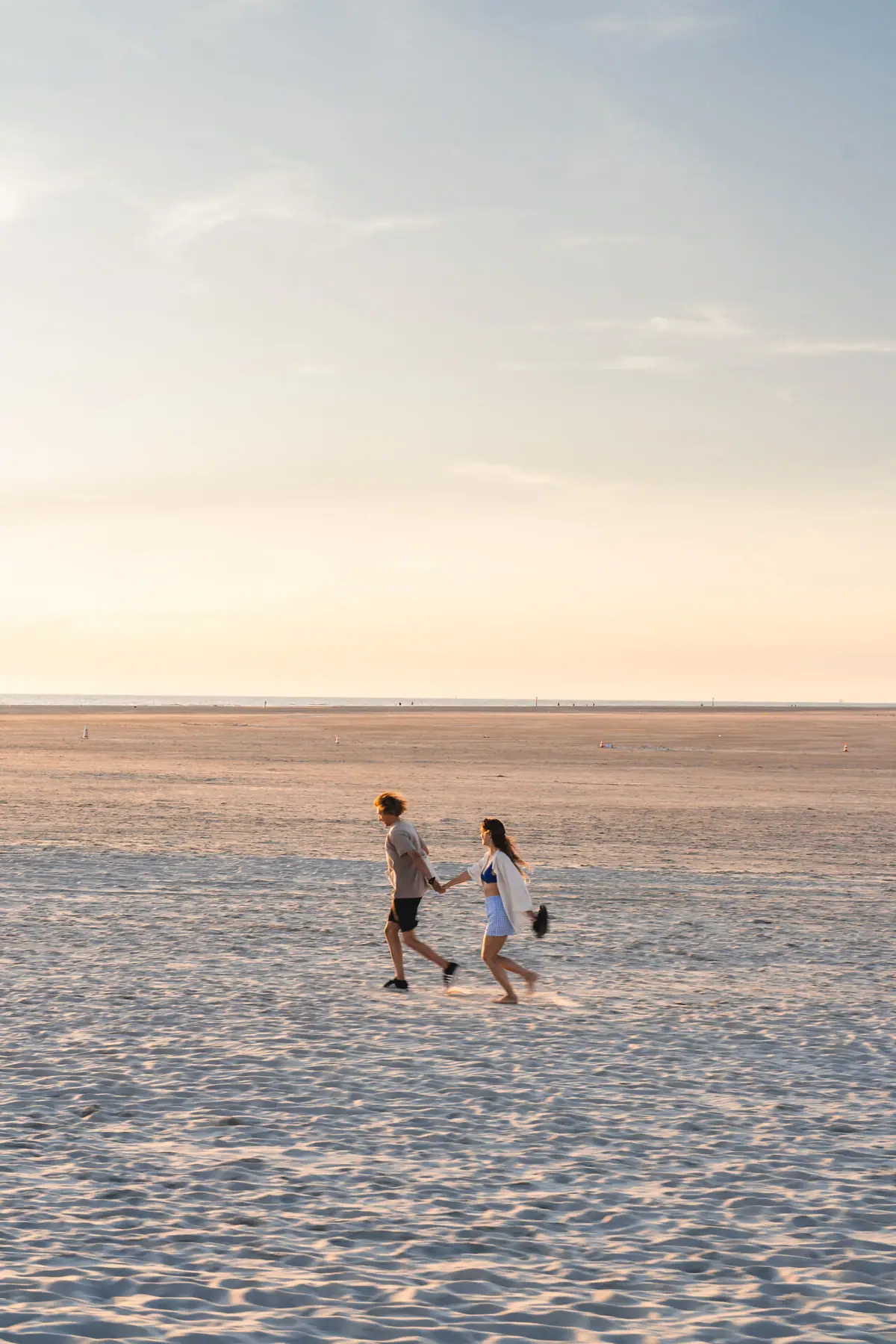 Strand von St. Peter-Ording Ein Mann und eine Frau halten sich an einem Strand an den Händen.