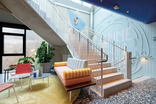 Design-Lounge mit bunter Sitzbank, farbenfroher Wandgestaltung und moderner Treppe in stylischem Hotelambiente