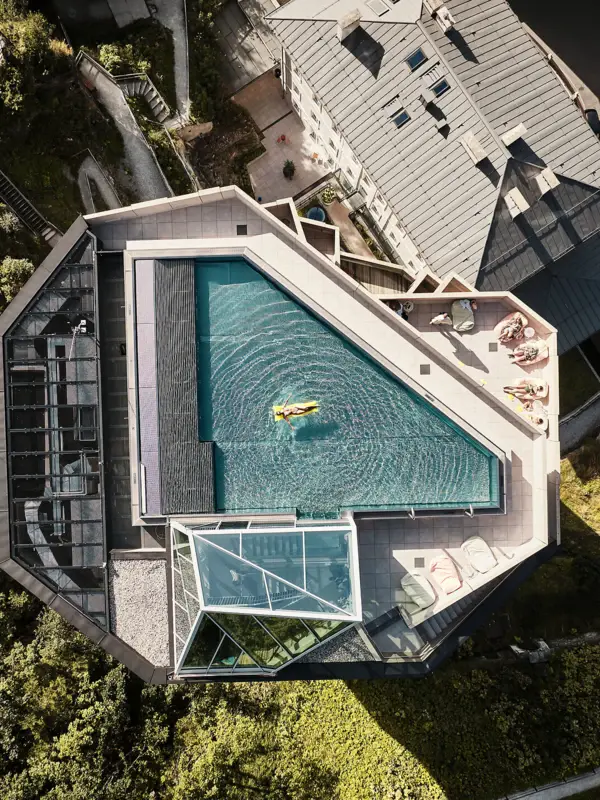 Ein schmales Gebäude mit einem Rooftop-Pool von oben fotografiert.