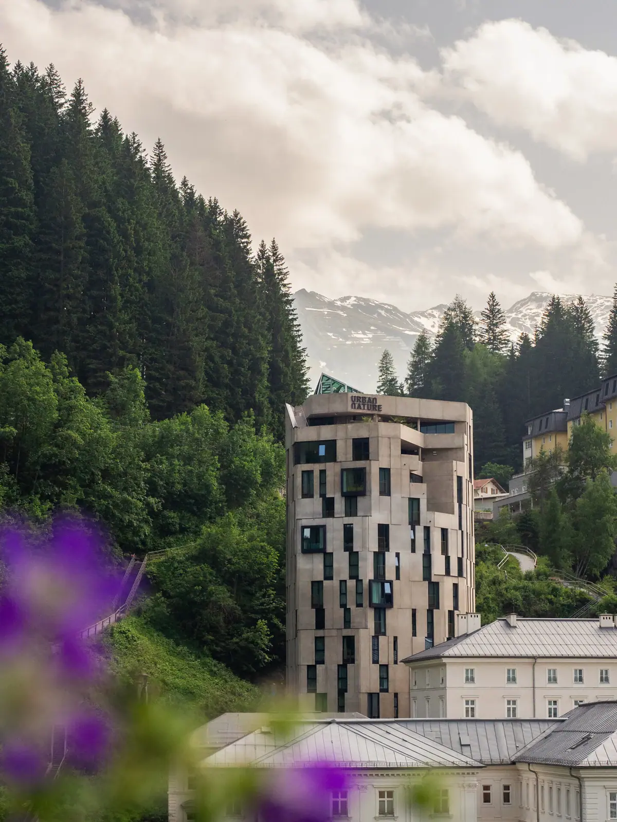 Urban Nature Bad Gastein Ein Gebäude mit Bäumen und Bergen im Hintergrund.