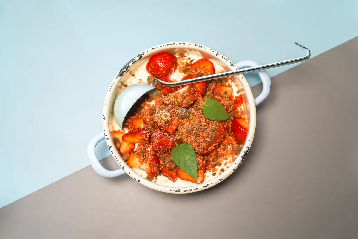 Tellergericht Auntie Clara Ein kleiner Topf mit einer Kelle und einem leckeren Gericht mit Tomaten darin.