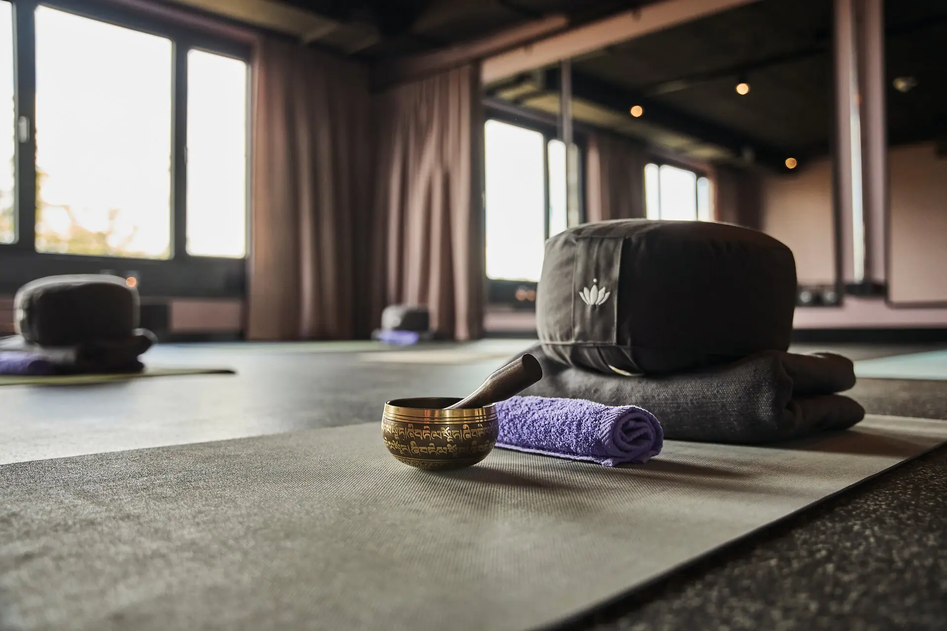 Yogaraum Urban Nature St. Peter-Ording Mehrere Yogamatten liegen in einem Yogaraum im Urban Nature Hotel St. Peter-Ording mit einer Klangschale, einem Handtuch, einem Sitzkissen und einer Decke.