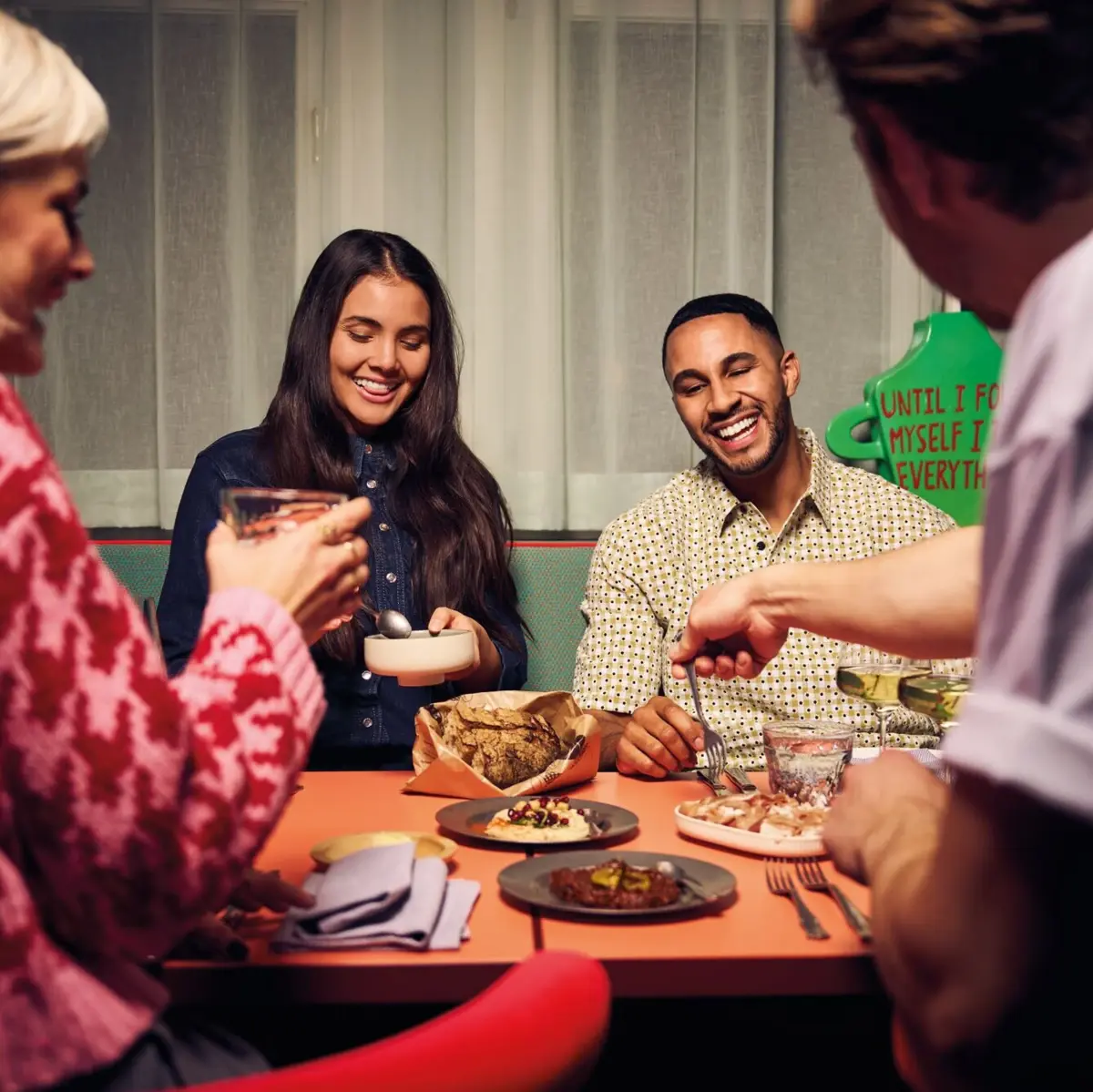 Gruppe junger Menschen beim gemeinsamen Essen – Lachen, Teilen und Genießen in geselliger Runde