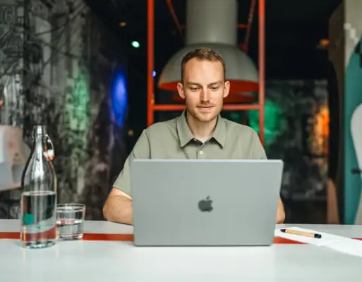 Ein Mann sitzt an einem Tisch mit einem Laptop.