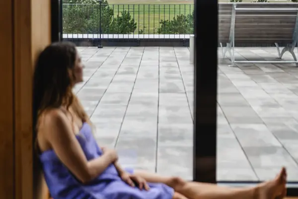 Eine Frau sitzt auf einer Fensterbank und schaut aus dem Fenster.