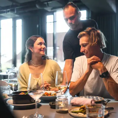 Eine Gruppe von Menschen sitzt an einem Tisch mit Essen und Weingläsern.