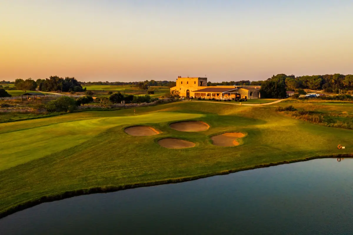Ein Haus steht hinter einem Golfplatz bei Sonnenuntergang.