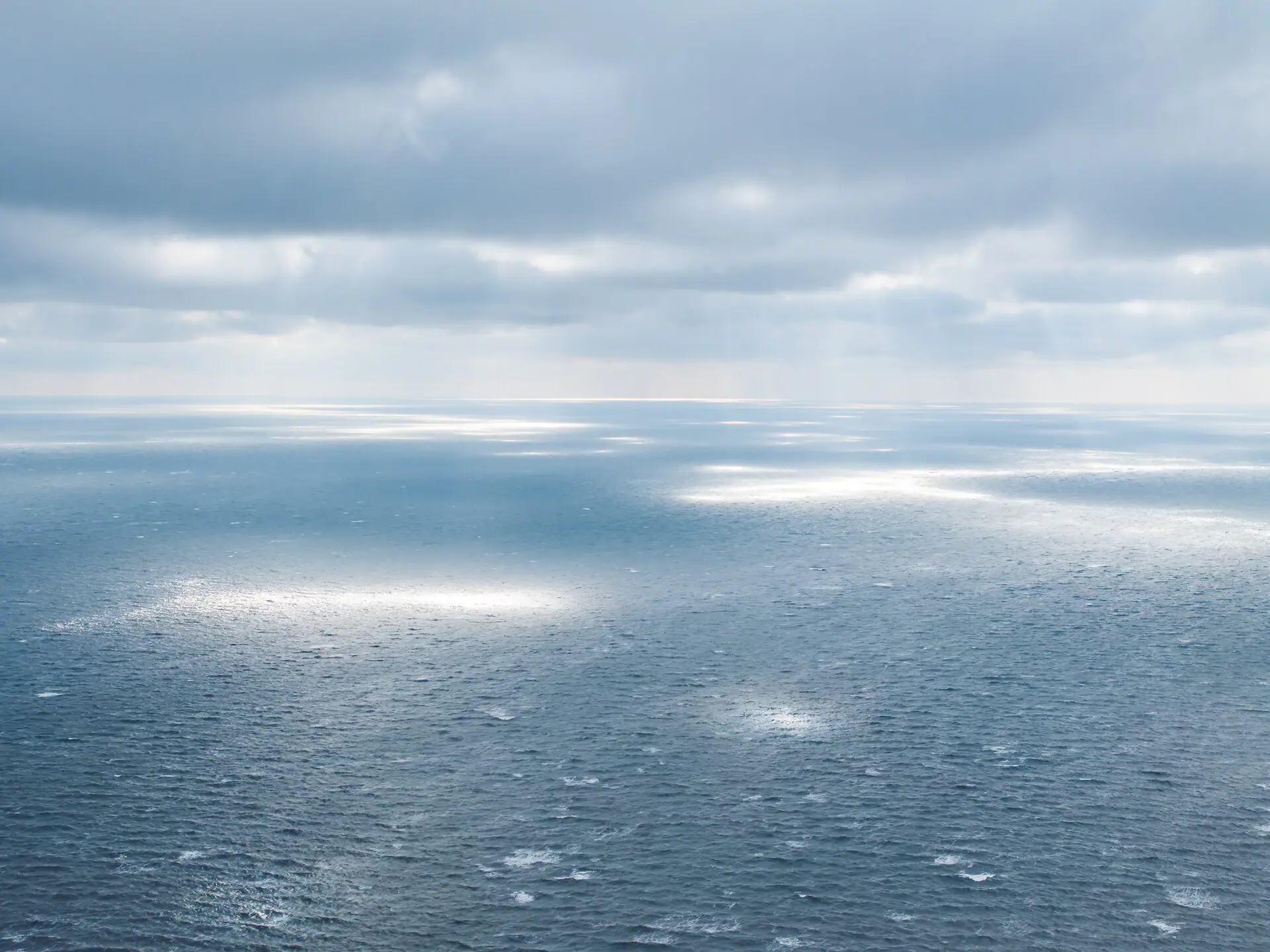 Großer Wasserkörper mit Sonnenstrahlen, die durch die Wolken scheinen.