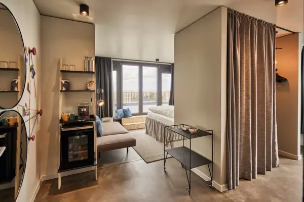 Eine Suite im Urban Nature Hotel St. Peter-Ording mit großen Fenstern und einer Terrasse.