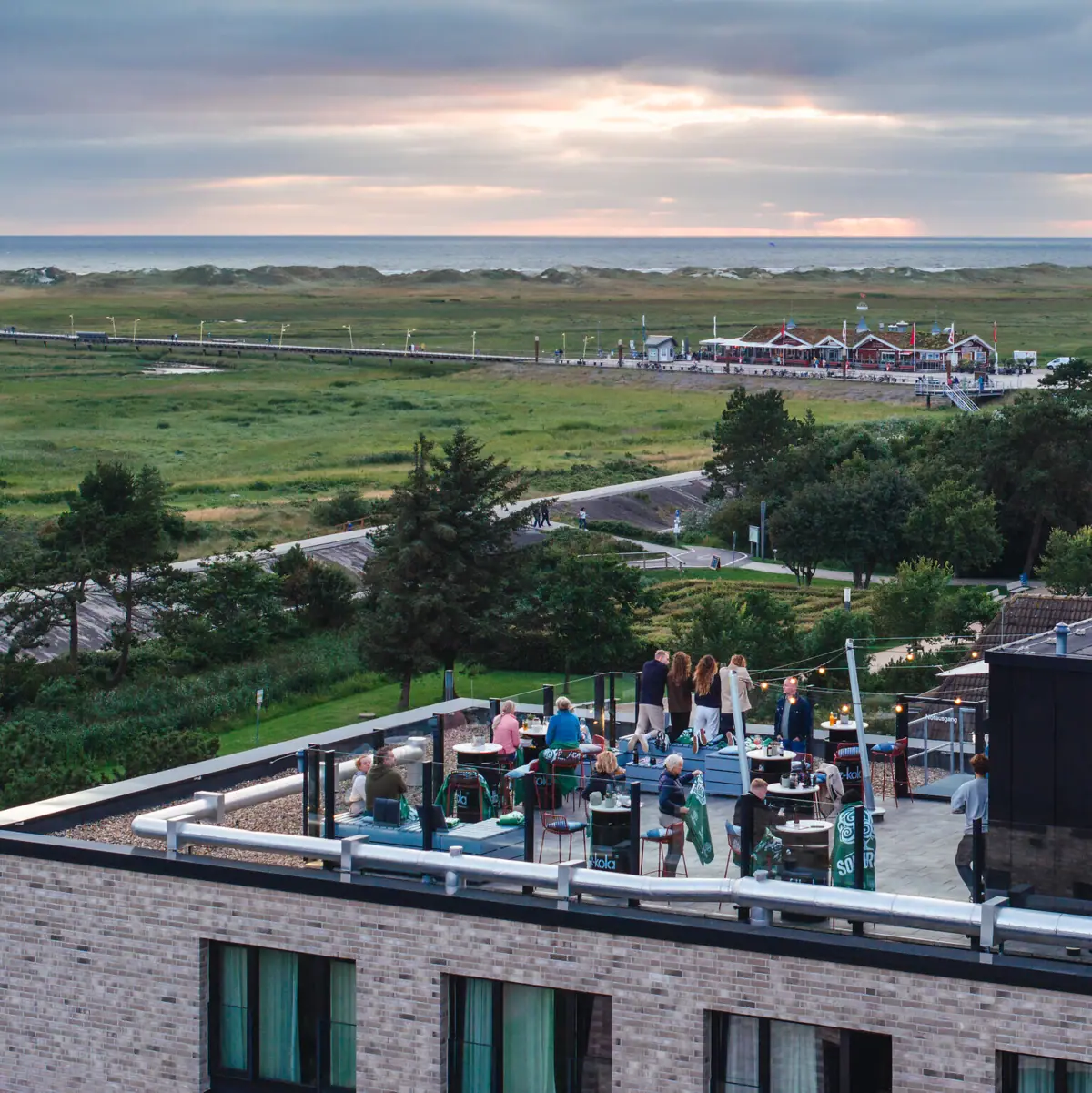 Menschen stehen auf der Rooftop-Bar vom Urban Nature Hotel St. Peter-Ording.